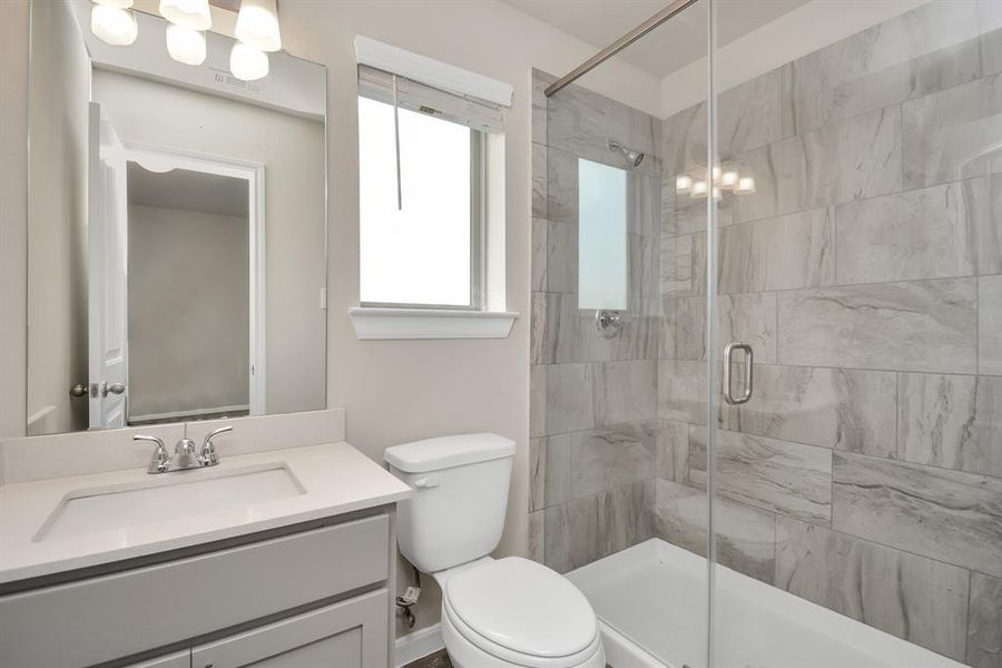 Retreat to this inviting ensuite bathroom, connected to the third bedroom, for a relaxing soak in the bathtub/shower combo. Sleek sliding glass doors add a touch of modern style, while the vanity with ample storage offers a designated space for toiletries. **This image is from another Saratoga Home with similar floor plan and finishes, not the Brittany floorplan.**