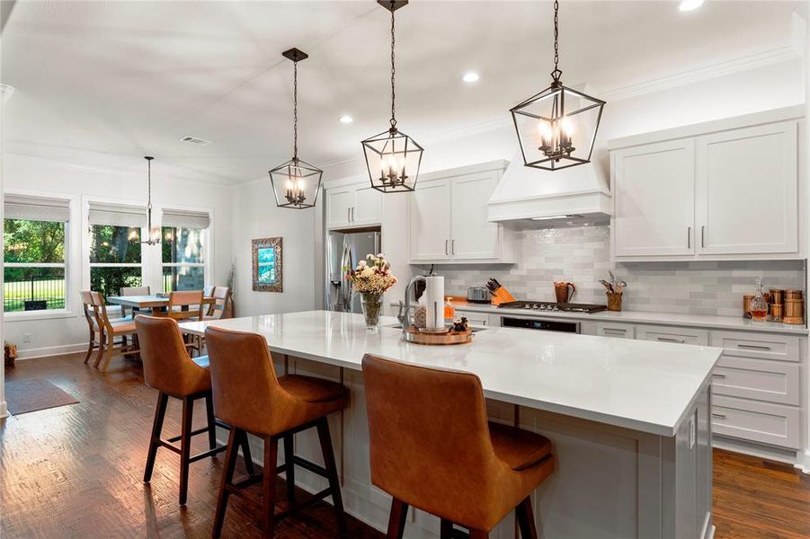 Kitchen featuring appliances with stainless steel finishes, pendant lighting, a breakfast bar area, and a large island with sink