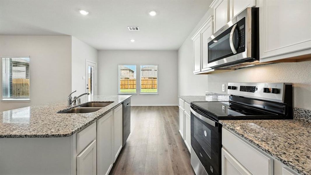 Kitchen featuring granite countertops, white cabinetry, stainless steel appliances, a double basin sink, and wood-finish flooring
