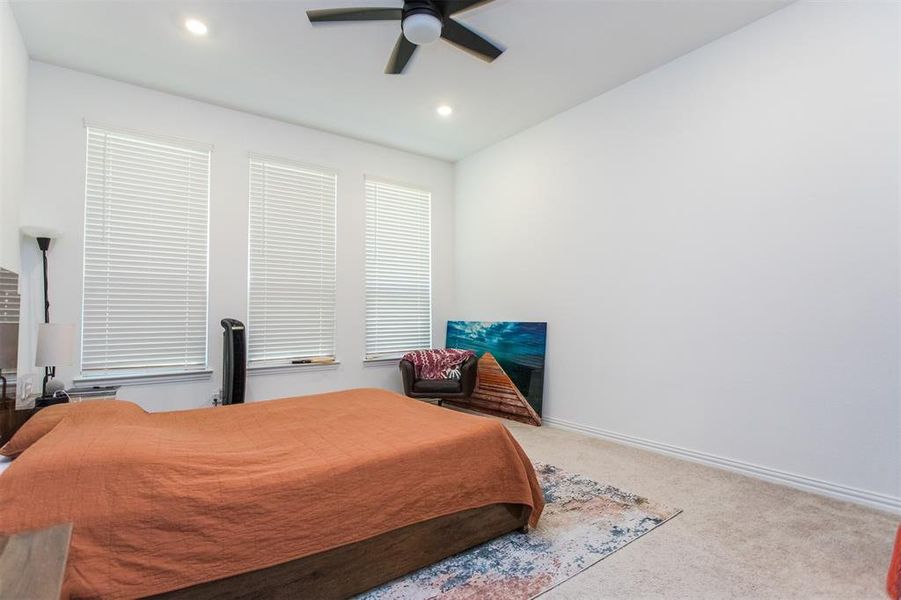 Carpeted bedroom featuring ceiling fan and vaulted ceiling