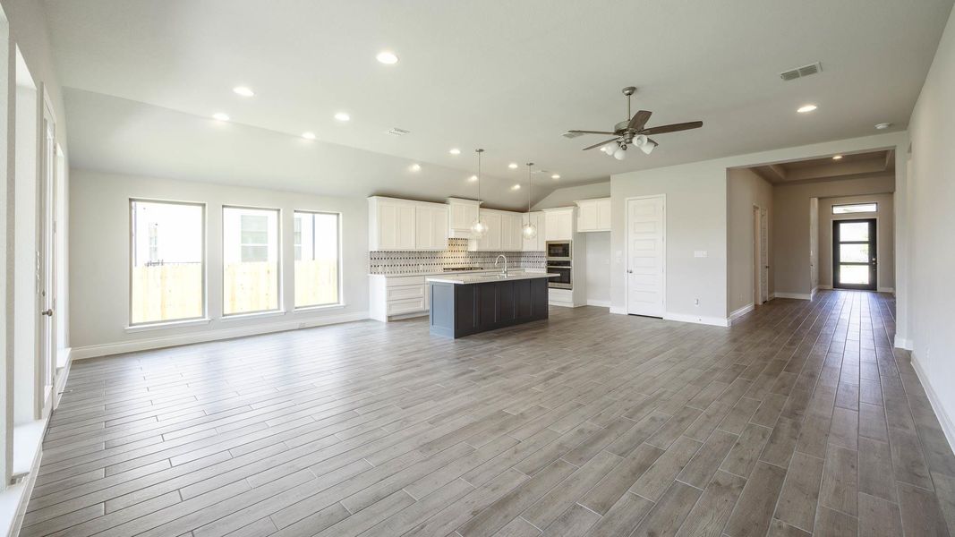 Kitchen featuring a kitchen island with sink, open floor plan, backsplash, baseboards, and lofted ceiling Kitchen featuring a kitchen island with sink, open floor plan, backsplash, baseboards, and lofted ceiling
