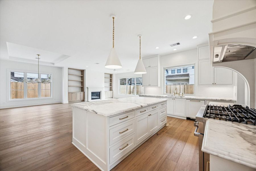 Quartz island anchors the kitchen with deep drawer storage and seating that keeps everyone connected to the living space. Designer pendant lighting, and seamless views into the family room, deliver an ideal layout for everyday living and large scale entertaining.