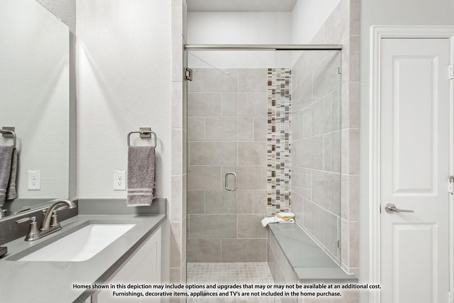 Bathroom with glass-door walk-in shower, gray tile walls, mosaic accent strip, and single vanity sink with gray countertop Bathroom with glass-door walk-in shower, gray tile walls, mosaic accent strip, and single vanity sink with gray countertop