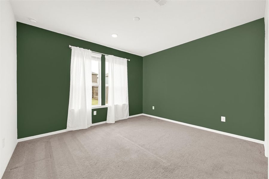 Cozy bedroom featuring a bold, stylish green accent wall and large window.
