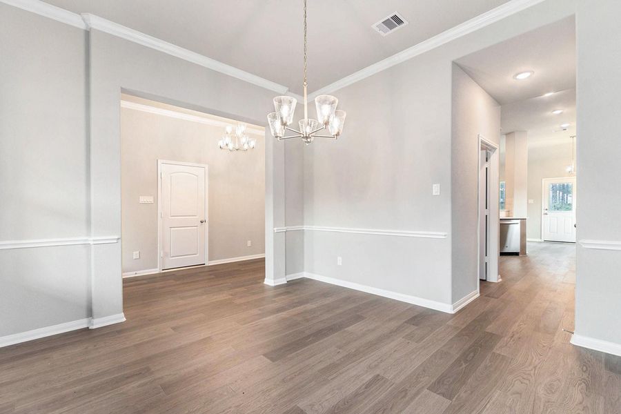 This spacious, well-lit room features elegant wood flooring, neutral wall colors, and stylish light fixtures, creating an inviting atmosphere. It includes a doorway leading to other areas, enhancing flow and functionality.