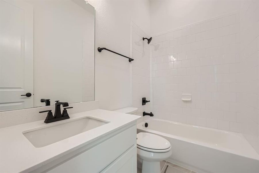 Full bathroom with toilet, tiled shower / bath, and vanity