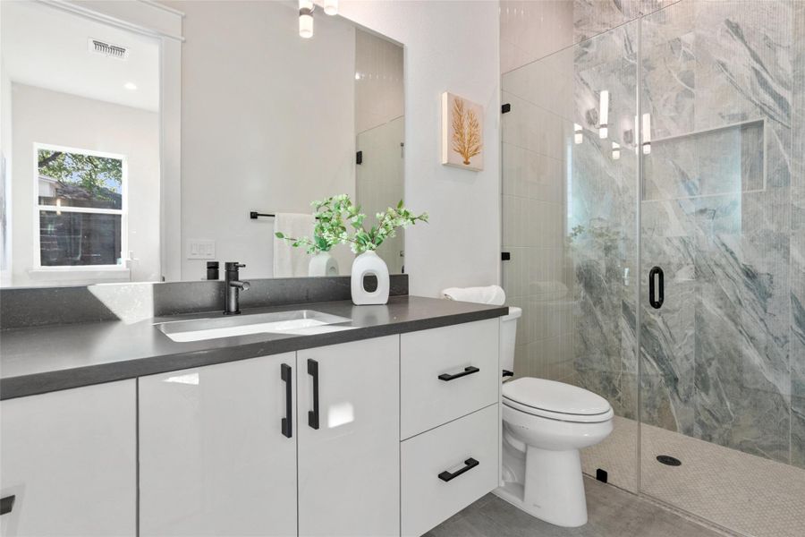 Bathroom featuring vanity, a marble finish shower, and a chandelier Bathroom featuring vanity, a marble finish shower, and a chandelier