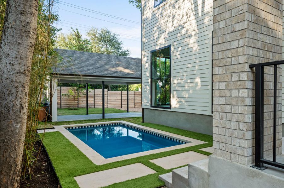 A private backyard oasis features a glistening pool, verdant lawn, and covered parking.