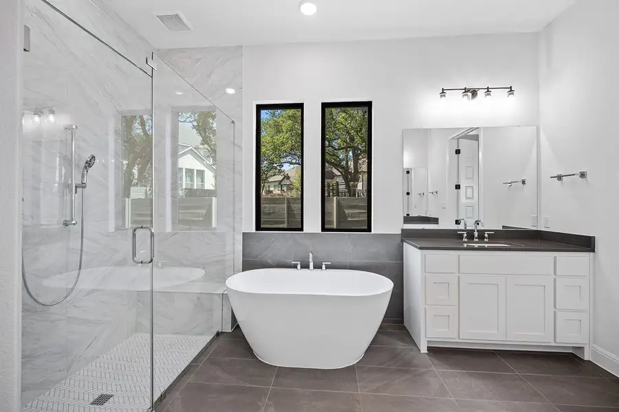 Full bathroom featuring a freestanding tub, a marble finish shower, vanity, and tile walls Full bathroom featuring a freestanding tub, a marble finish shower, vanity, and tile walls