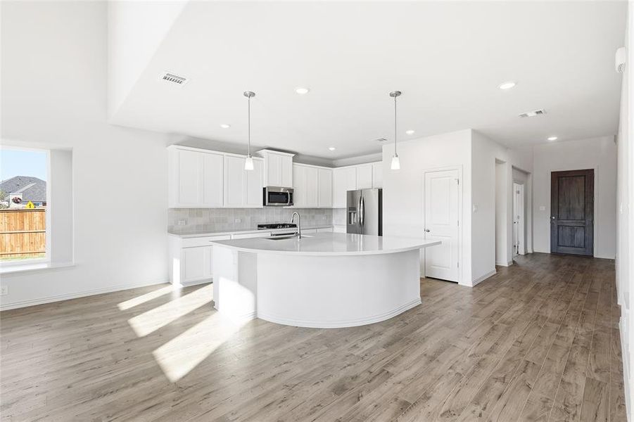 Kitchen with stainless steel appliances, white cabinetry, hanging light fixtures, a kitchen island with sink, and recessed lighting