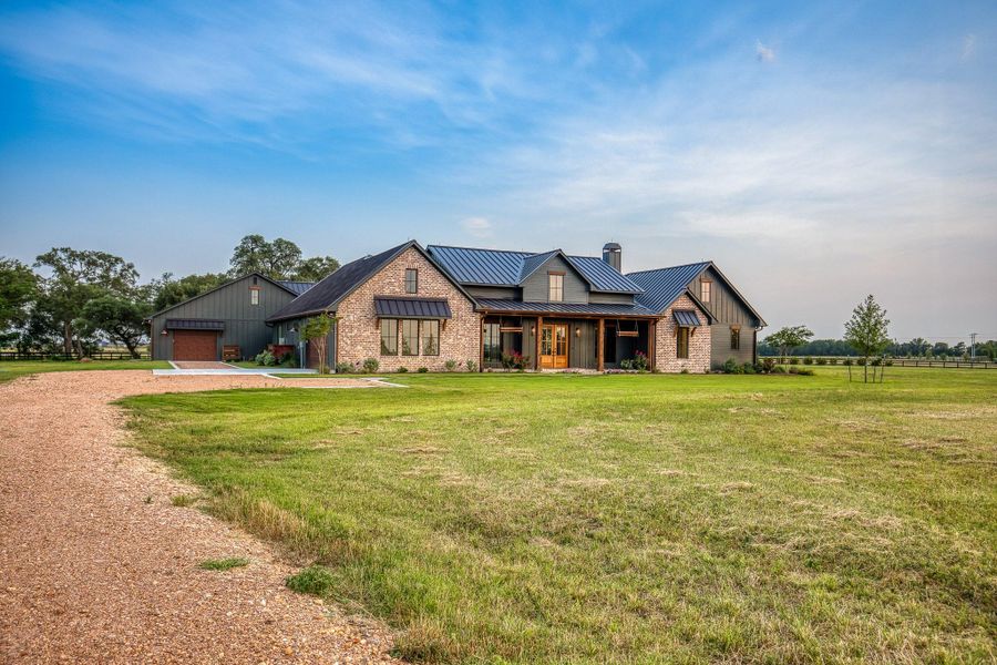View of front of house with a chimney, a garage, driveway, a metal roof, and a standing seam roof View of front of house with a chimney, a garage, driveway, a metal roof, and a standing seam roof