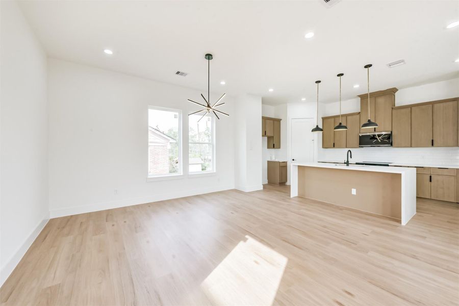 The living room opens up to the dining room showcasing a sleek and modern light fixture.