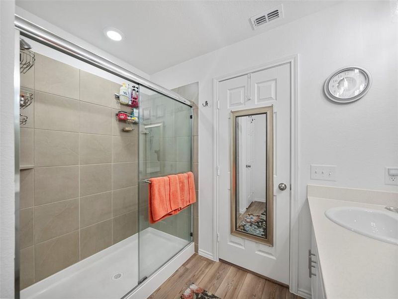 Full bathroom with vanity, wood finished floors, a shower stall, and visible vents