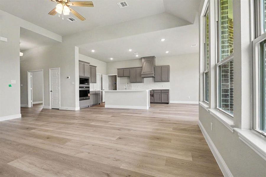 Open-concept living space featuring wood-finish flooring, recessed lighting, and high ceilings Open-concept living space featuring wood-finish flooring, recessed lighting, and high ceilings