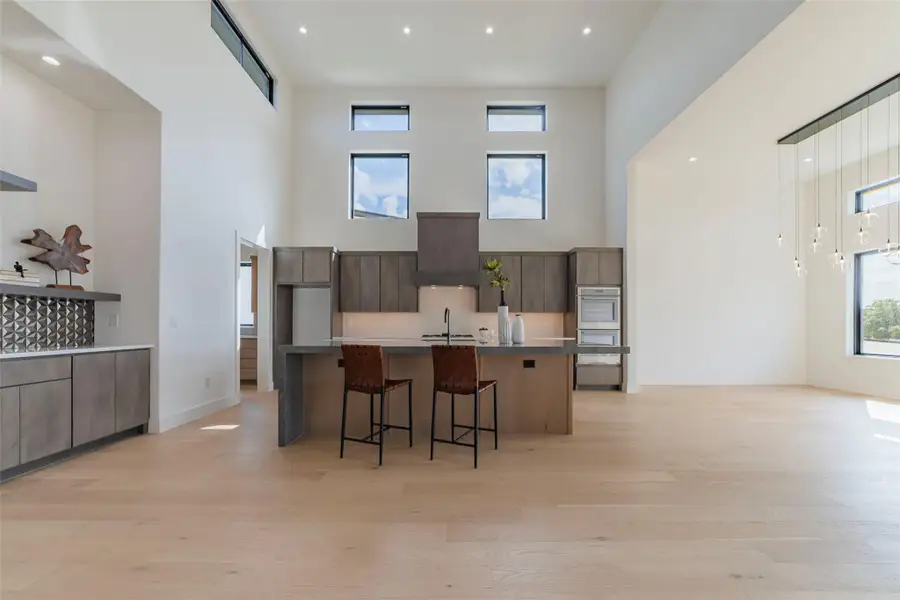 Kitchen with a breakfast bar area, recessed lighting, a large island with sink, light wood-type flooring, and modern cabinets