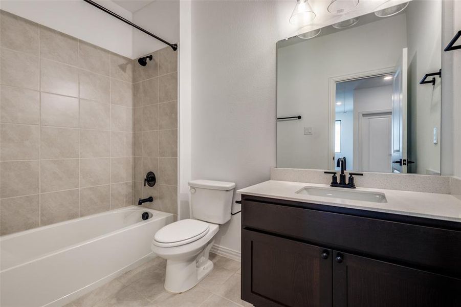 Full bathroom featuring tile patterned flooring, vanity, tiled shower / bath combo, and toilet