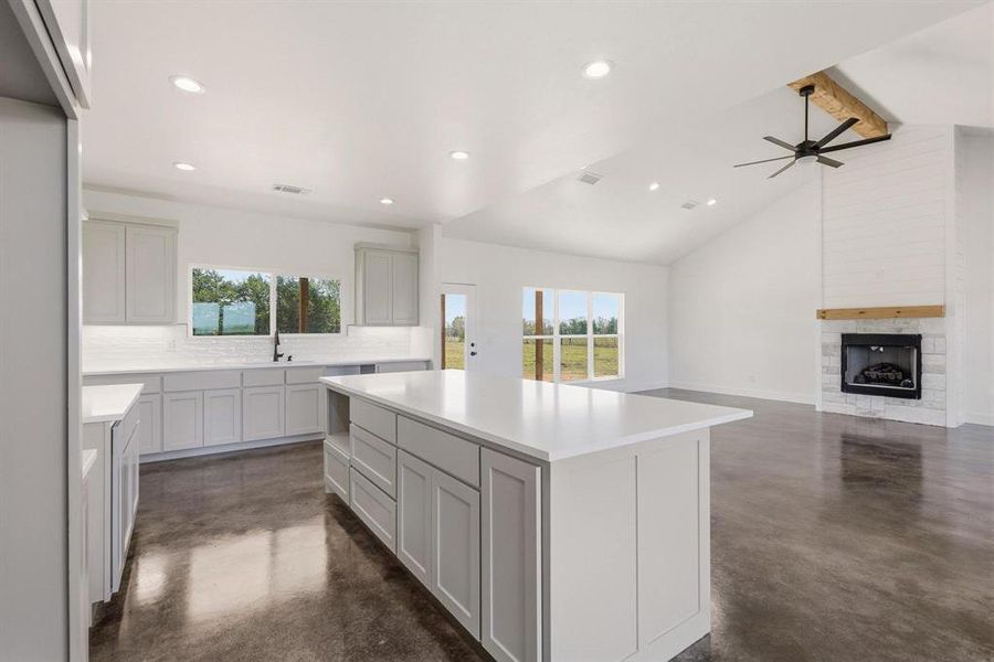 The property features an open-concept living area with vaulted ceilings, recessed lighting, and polished concrete floors
