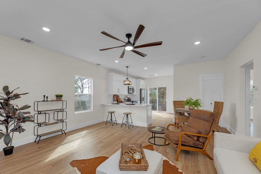 Living room featuring light wood finished floors, ceiling fan, plenty of natural light, and recessed lighting