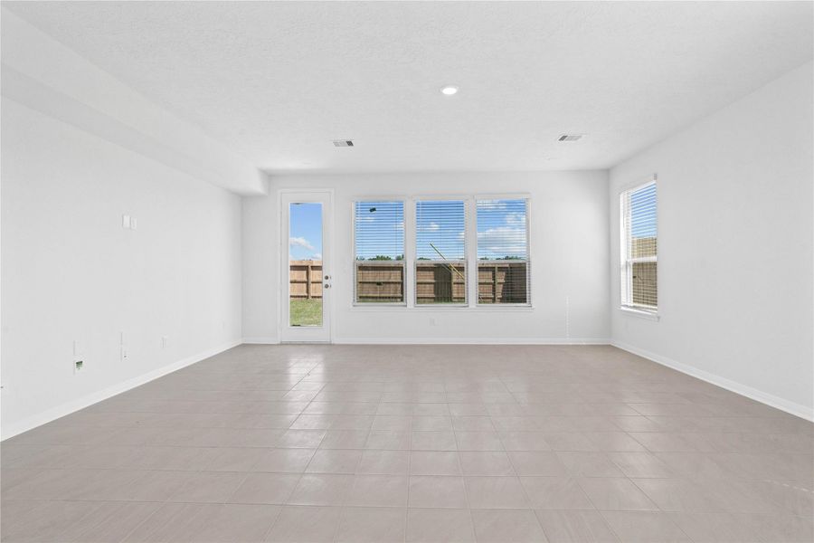 This bright and airy Great Room offers a spacious layout ideal for both relaxing evenings and lively gatherings. Designed for comfort and connection, it features ceramic tile flooring, large windows with blinds, soaring ceilings, recessed lighting, and seamless access to the stunning kitchen and dining—perfect for everyday living and entertaining alike.