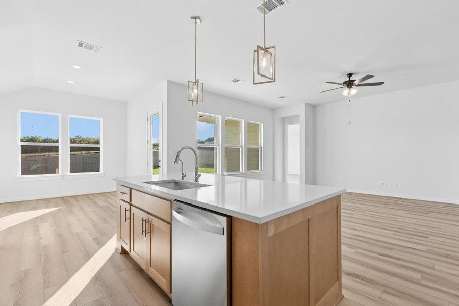 Kitchen with open floor plan, decorative light fixtures, stainless steel dishwasher, light wood finished floors, and ceiling fan
