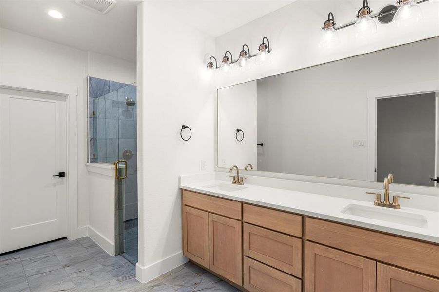 Full bathroom featuring a shower stall, double vanity, light marble finish floors, and recessed lighting