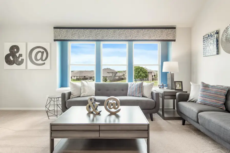 Living room with gray sofas, large triple window with blue accents, and decorative coffee table on carpet