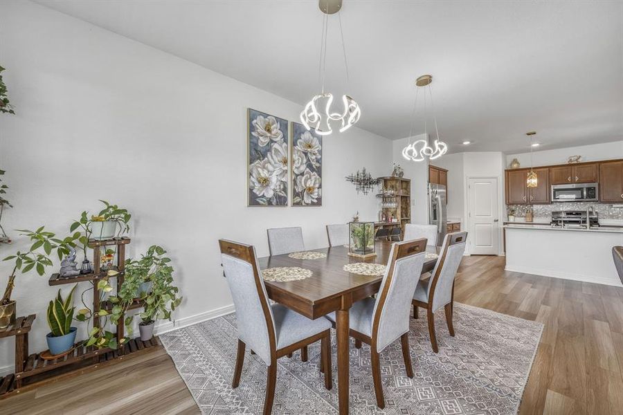 Open-concept dining area featuring wood-finish flooring, two contemporary pendant light fixtures, and a decorative area rug Open-concept dining area featuring wood-finish flooring, two contemporary pendant light fixtures, and a decorative area rug