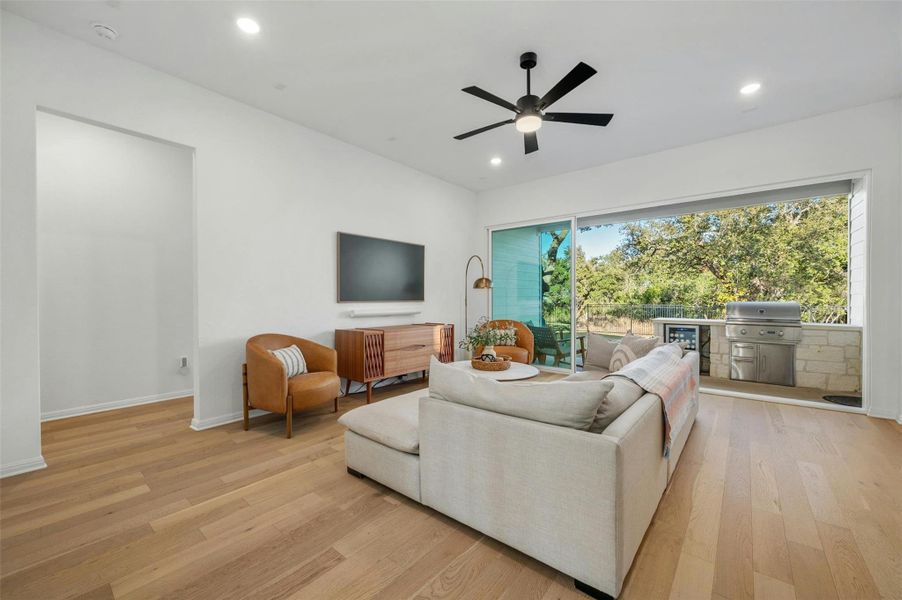 Your living room opens seamlessly onto the covered back porch through oversized glass sliders that frame serene greenbelt views.