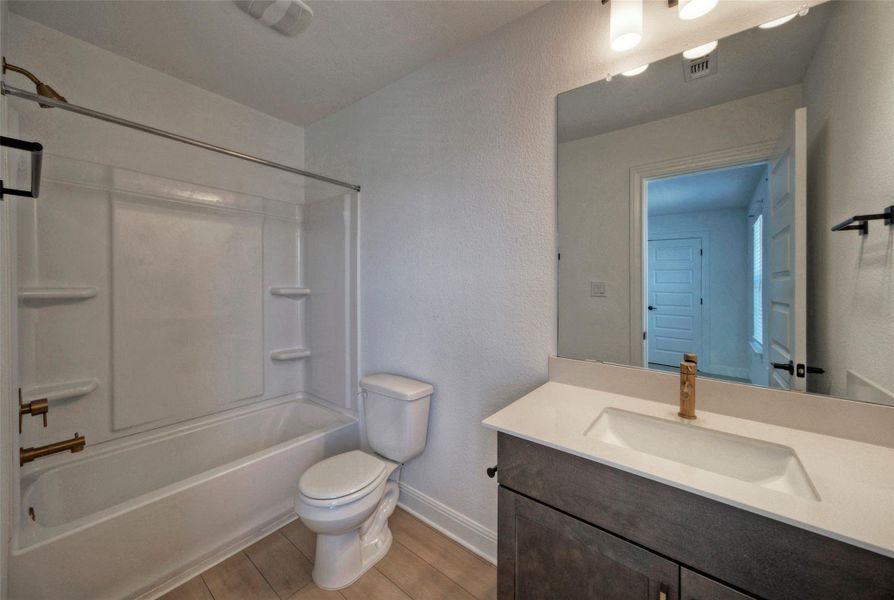 A clean bathroom features a modern vanity with stone counters and wood-look flooring. A clean bathroom features a modern vanity with stone counters and wood-look flooring.