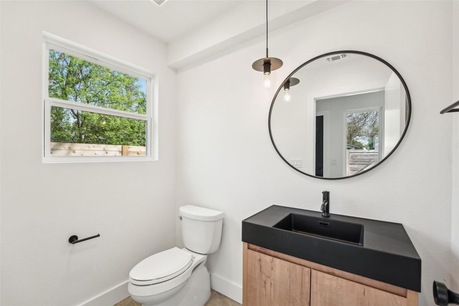 Half bath featuring baseboards, toilet, and vanity