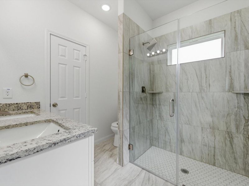 The primary en-suite is thoughtfully finished with dual sinks, a sleek glass-enclosed shower, and a spacious walk-in closet designed for everyday comfort.