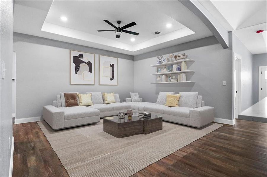 Living room featuring hardwood / wood-style flooring, ceiling fan, and a tray ceiling