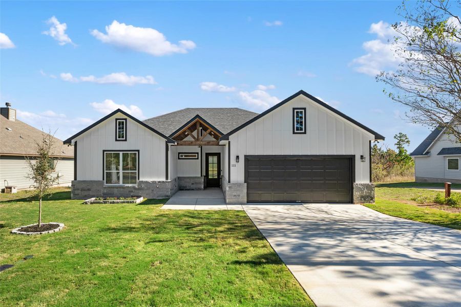 Modern farmhouse style home featuring board and batten siding, a front lawn, and concrete driveway
