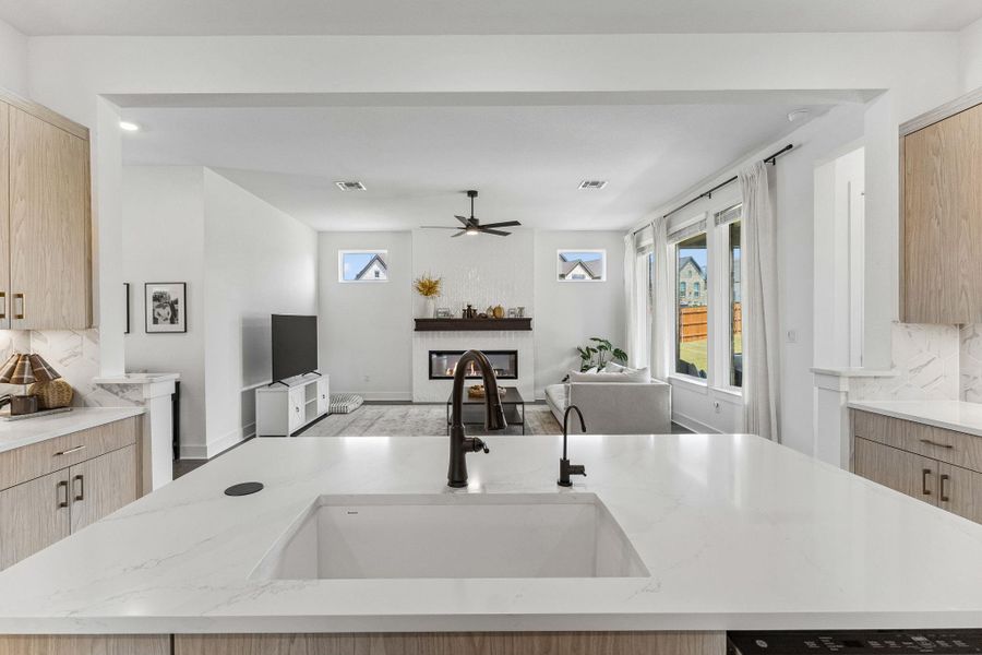 An open floorplan seamlessly connects the stone counters of this modern kitchen to the living area.