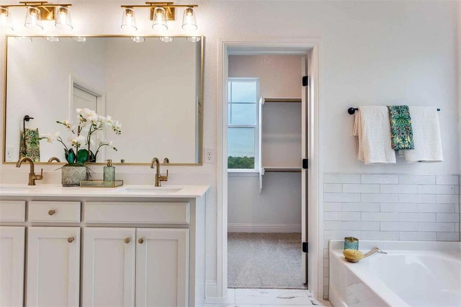 Full bathroom featuring double vanity, a bath, and a walk in closet