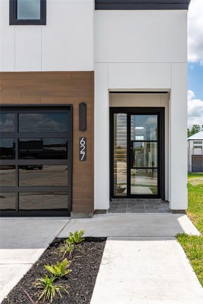 A bold wrought iron entry door with tempered glass inserts makes a striking first impression, setting the tone for the sophistication within A bold wrought iron entry door with tempered glass inserts makes a striking first impression, setting the tone for the sophistication within