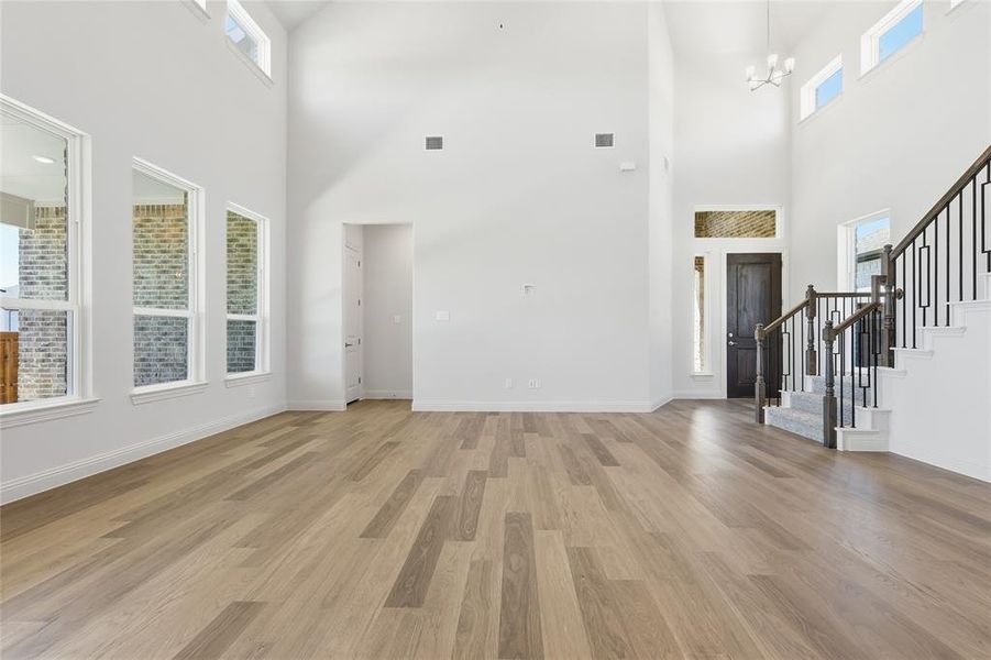 Entrance foyer with light wood-type flooring, a high ceiling, and suspended lighting