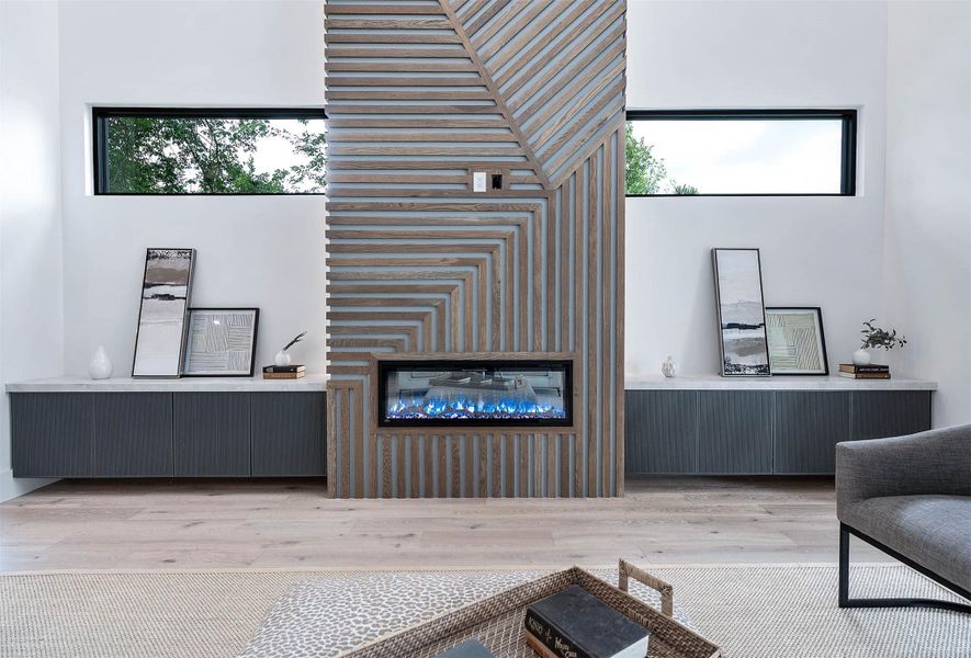 Living room centerpiece features a dramatic 23.5-foot-tall LED fireplace framed by custom millwork, combining striking modern design with elegant craftsmanship to create a captivating focal point.