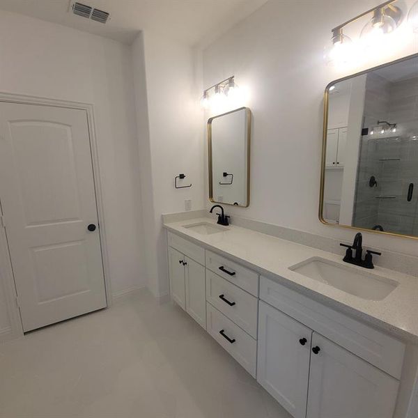 Bathroom featuring tiled shower, tile flooring, oversized vanity, and double sink