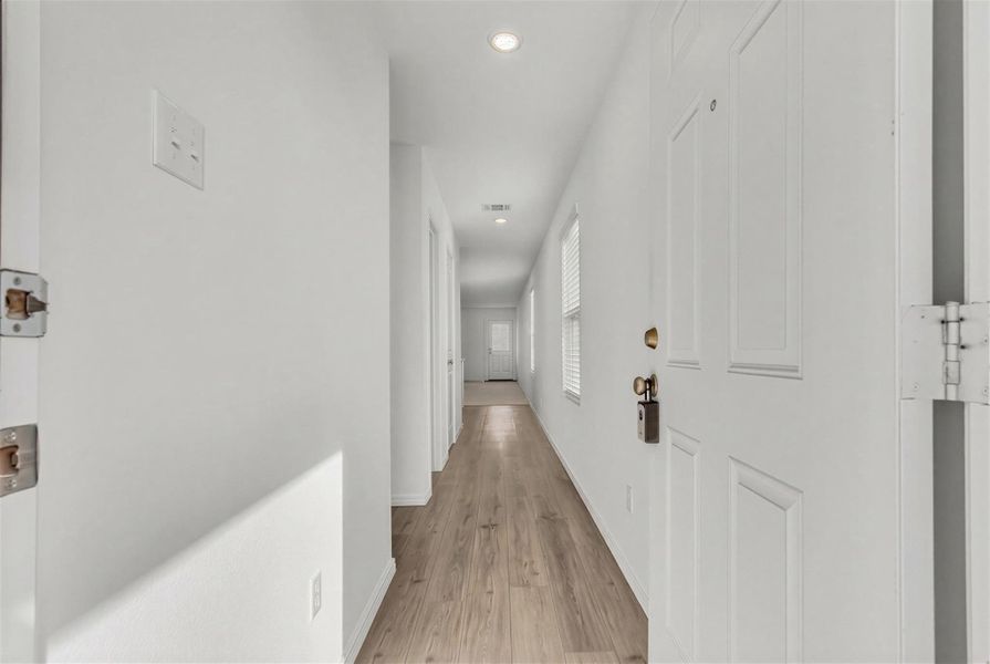 Smooth wood-look flooring guides visitors down a long, light-filled entry hallway. Smooth wood-look flooring guides visitors down a long, light-filled entry hallway.