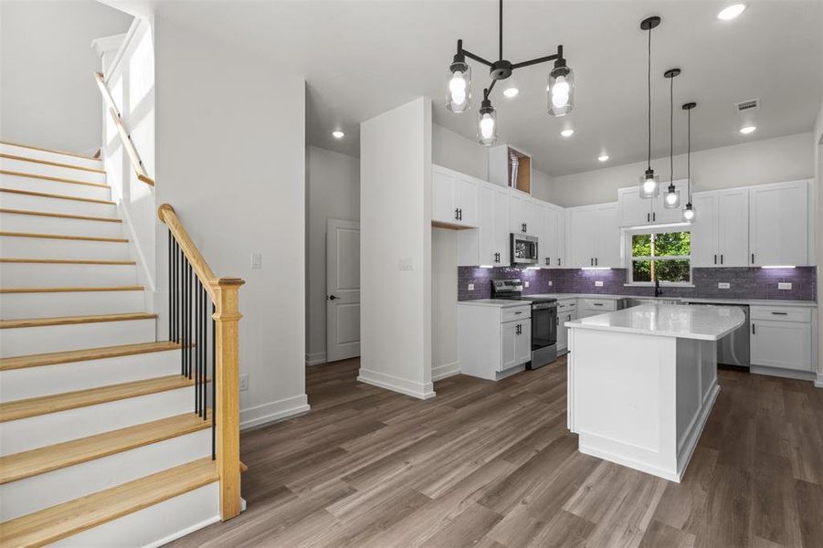 The property features a bright kitchen with white cabinetry, stainless steel appliances, and a central island with a white countertop