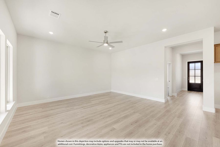 Empty living room with light wood floors, white walls, ceiling fan, and view to front entry door Empty living room with light wood floors, white walls, ceiling fan, and view to front entry door