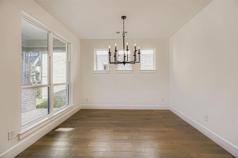Unfurnished dining area featuring dark wood-type flooring and a chandelier Unfurnished dining area featuring dark wood-type flooring and a chandelier