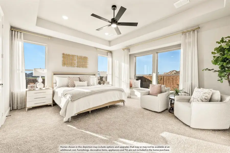 Master bedroom with tray ceiling, ceiling fan, carpet flooring, and large windows with seating area