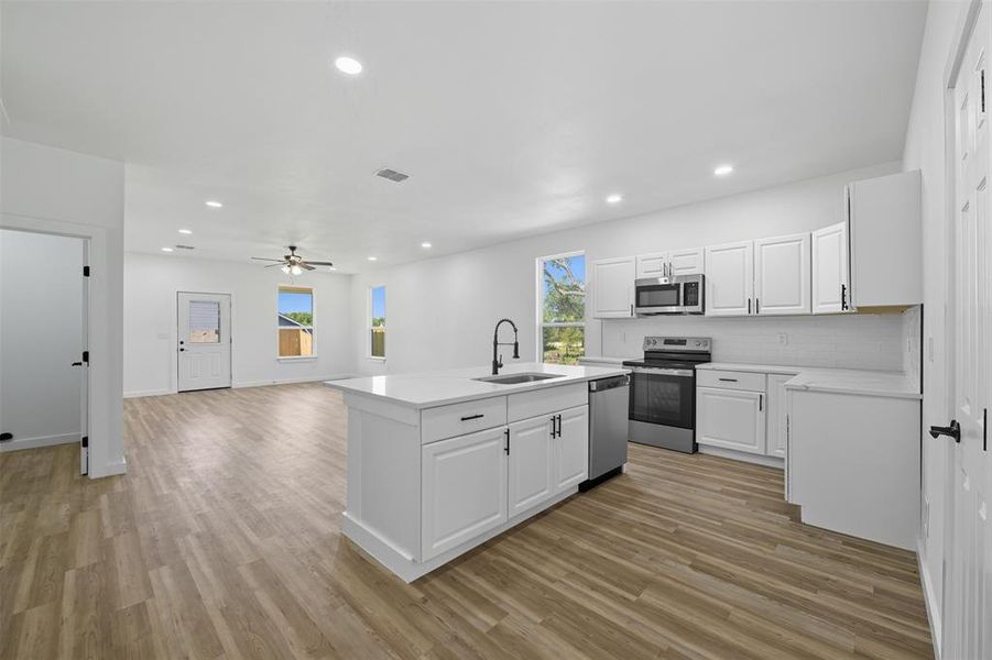 Kitchen with white cabinets, stainless steel appliances, recessed lighting, tasteful backsplash, and light wood-type flooring Kitchen with white cabinets, stainless steel appliances, recessed lighting, tasteful backsplash, and light wood-type flooring