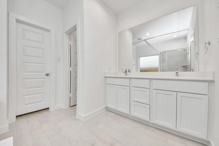 Elevate your daily routine at the elegant vanity, now equipped with double sinks, light countertops, modern hardware, and beautiful recessed lights.