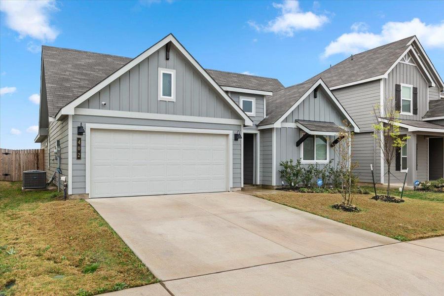 View of front facade with board and batten siding, a shingled roof, and concrete driveway