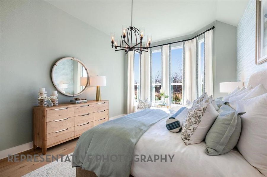 Bedroom with wood finished floors, a chandelier, and lofted ceiling