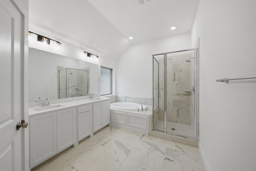 Full bathroom with double vanity, a marble finish shower, a garden tub, vaulted ceiling, and light marble finish floors