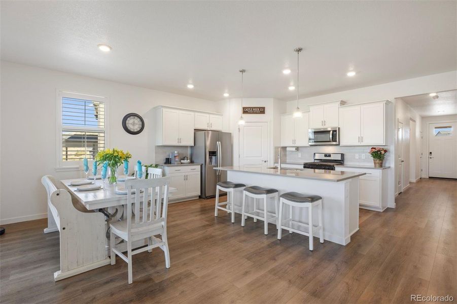 Bright, open kitchen with a large quartz island, breakfast bar seating, and dining area.